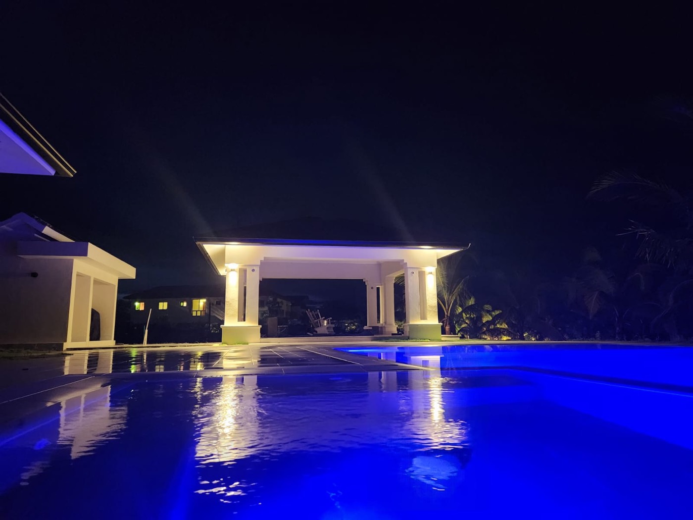 Piscina iluminada en azul de noche con gazebo