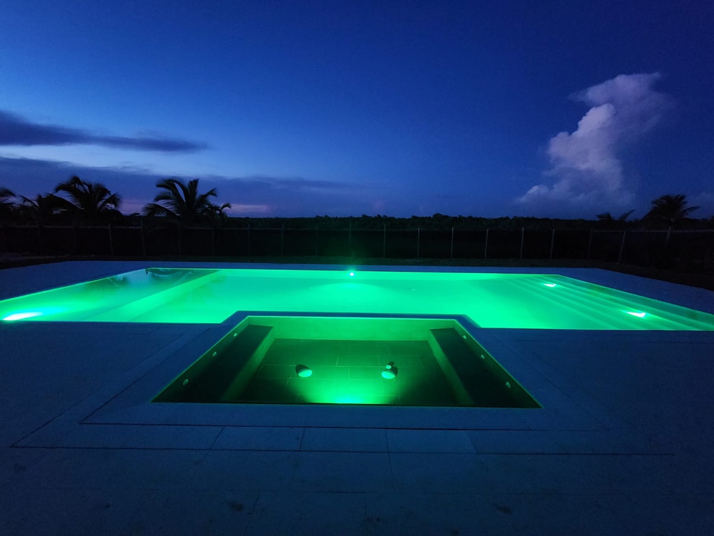 Piscina y jacuzzi iluminados en verde